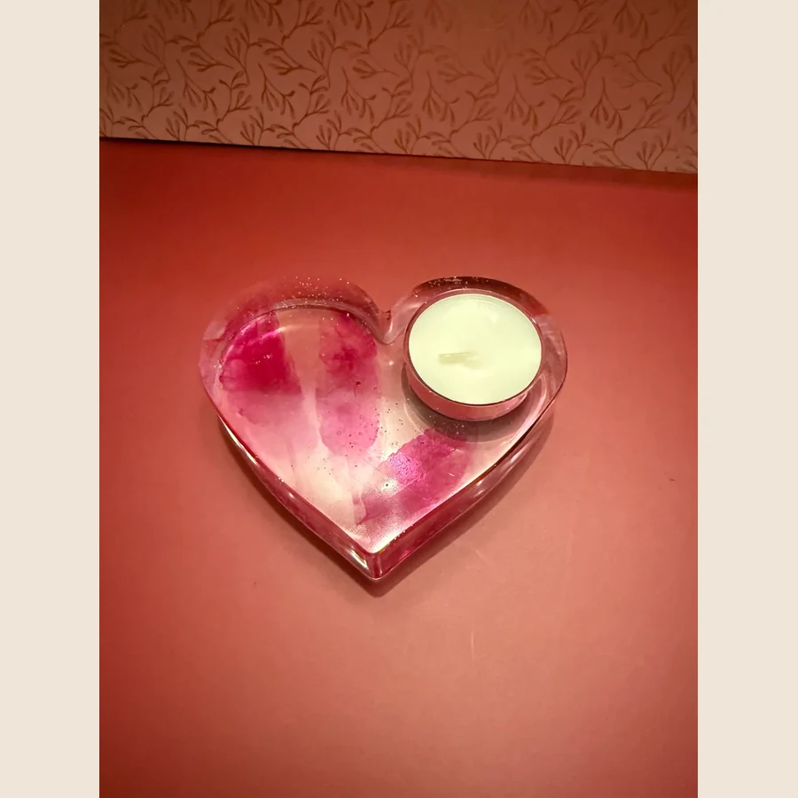Waxine licht houder met roze veren erin verwerkt. Gemaakt van epoxy, ook de veren die erin liggen.